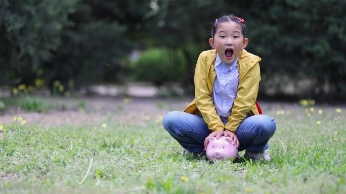 亚洲小女孩抱着小猪银行惊讶不已