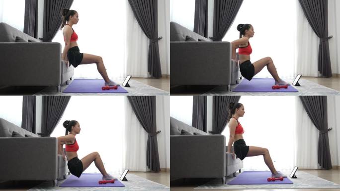 年轻的肌肉健身女性在家中客厅、沙发上做半蹲运动