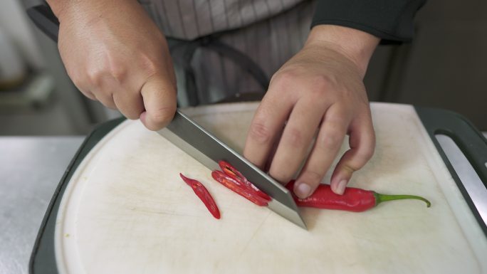 厨师将红辣椒切成小块，用作泰国食物的配料