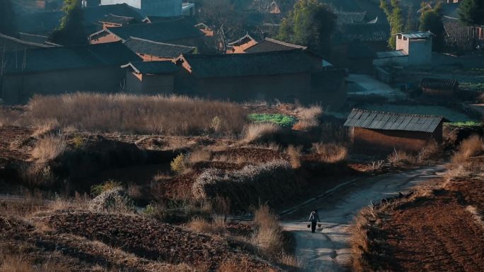 贫困乡村云南山区土房村庄小路上提水桶的人