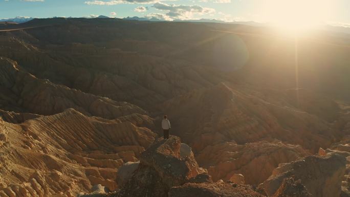 女孩站在夕阳下的西藏阿里札达土林悬崖边