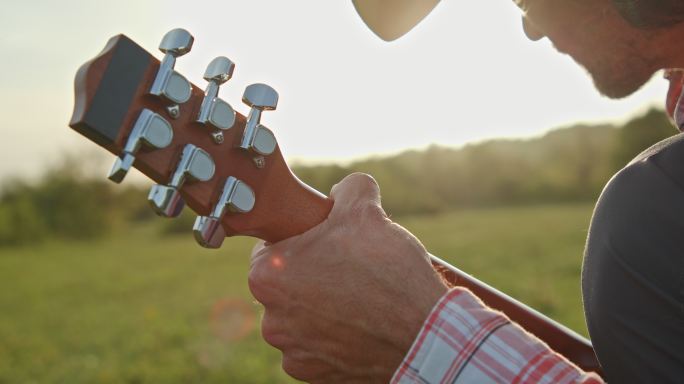 大自然中的牛仔在日落时弹吉他。春季住宿。