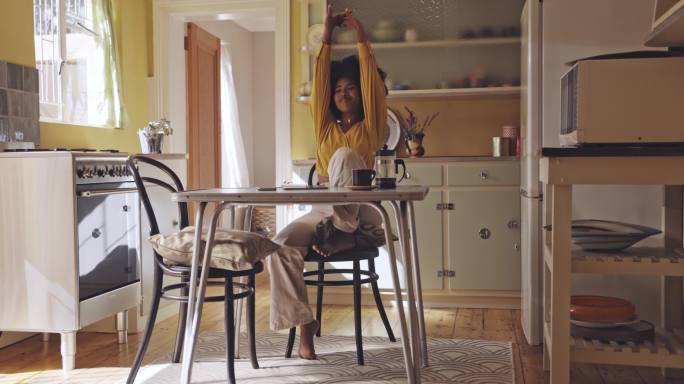 年轻女性在家休息和拉伸。早上在厨房放松一下，为一天做好准备。快乐的女人在她的公寓里喝咖啡和写日记