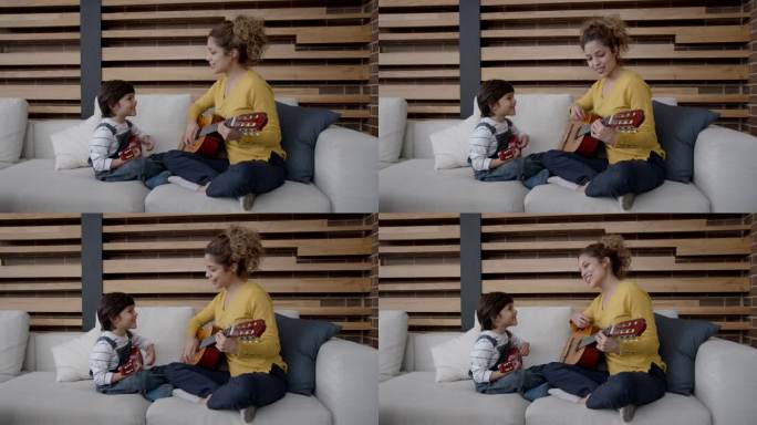 美丽的年轻妈妈和她的儿子一起弹吉他，笑着唱歌都很开心