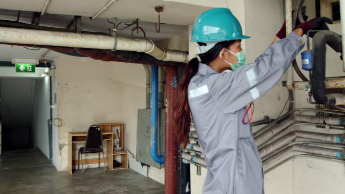 亚洲女技术员检查员检查大楼内的空调泄漏情况。工程师女性触摸