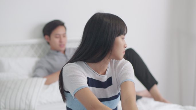 悲伤的亚洲女人躺在床上，不幸福的夫妻有感情问题。