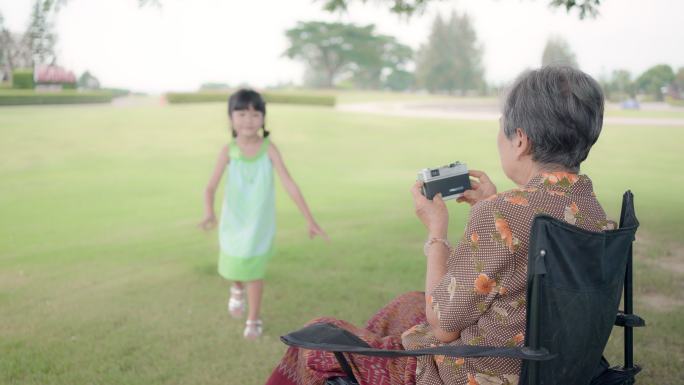 奶奶和孙女在公园里玩耍，拍摄相机，玩秋千，母亲节，家庭日的概念。