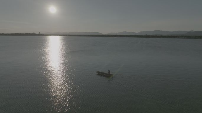 夕阳下渔民在湖面上撒网捕鱼