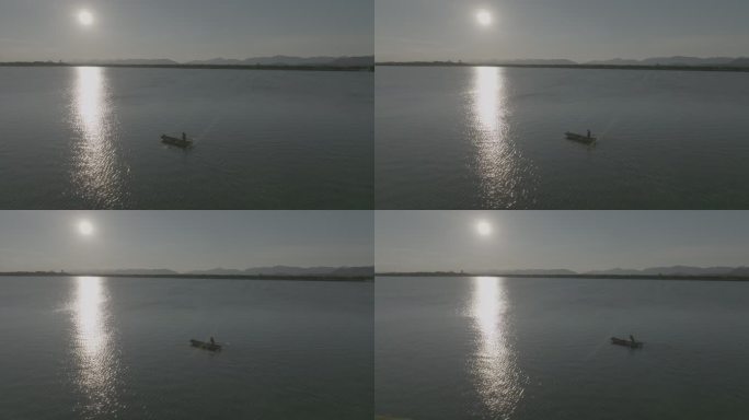 夕阳下渔民在湖面上撒网捕鱼