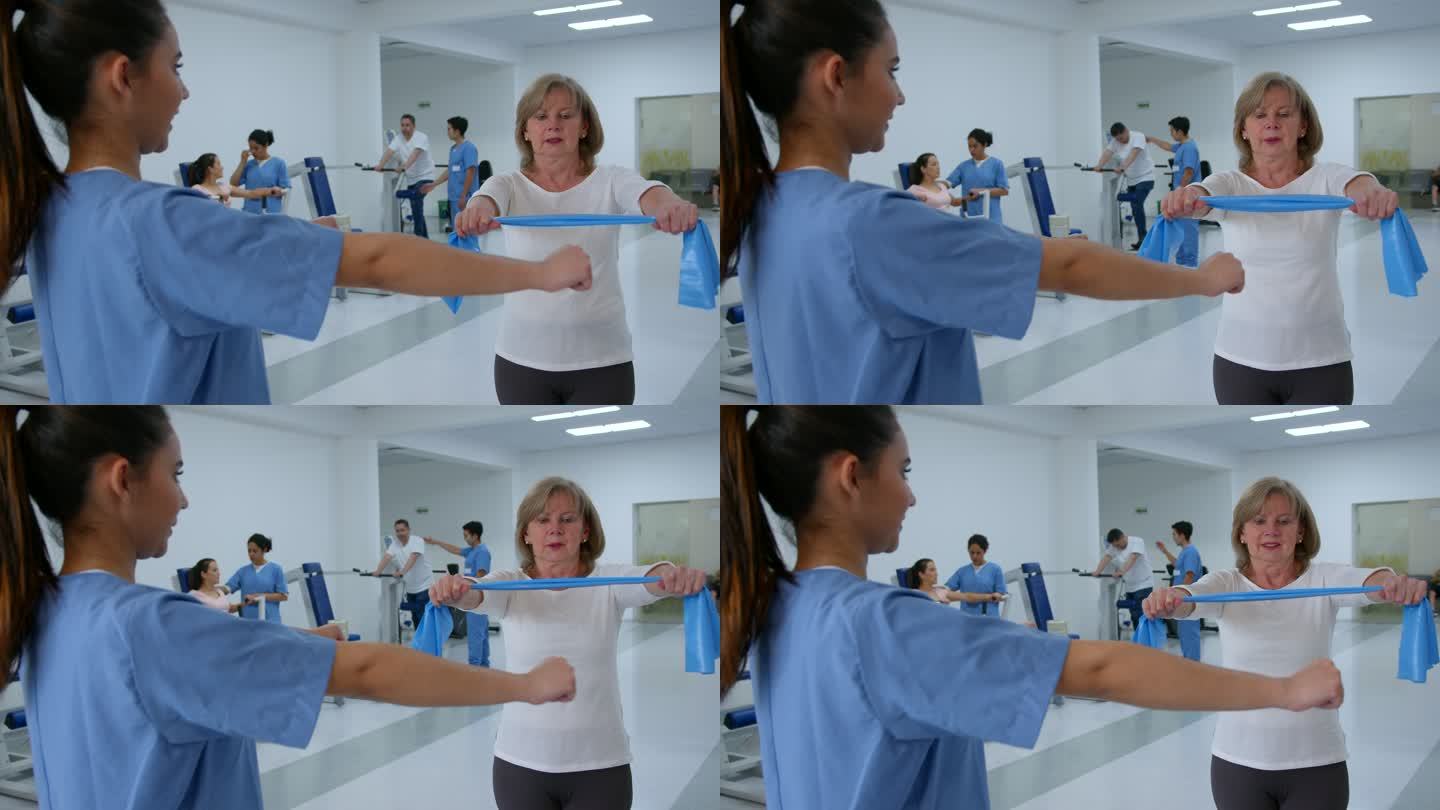 一名老年妇女在康复诊所按照治疗师的指示，用阻力带锻炼手臂