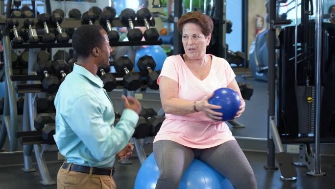 物理治疗师与老年女性一起使用健身球