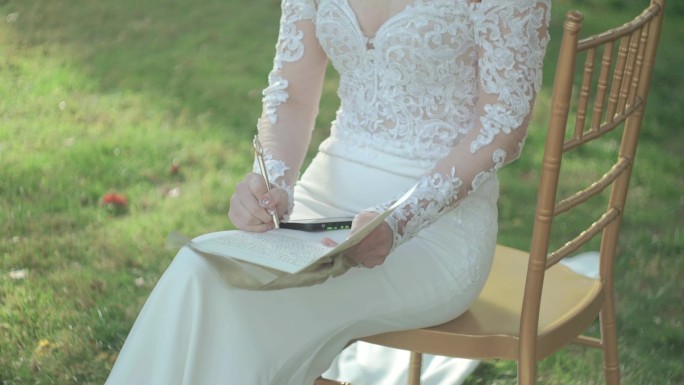 坐在凳子上的写誓言卡的新娘子
