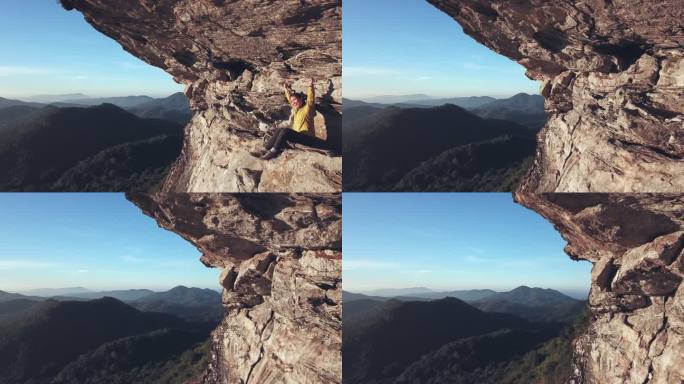 空中拍摄的坐在山上悬崖上的女徒步旅行者