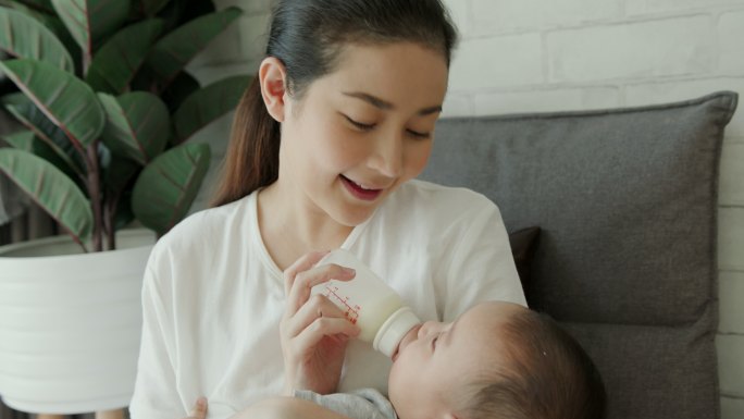 单亲妈妈坐在家里给她可爱的新生男婴喂奶。婴儿