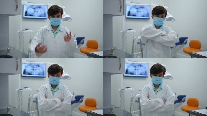 一个可爱的小男孩在牙医那里练习假装穿着实验服，戴着防护面罩，交叉双臂面对镜头