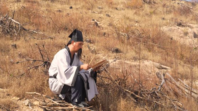 古代文人坐在山坡上看书