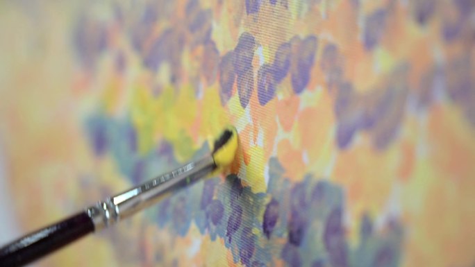 有颜料的画笔在画布上画暖色调的画