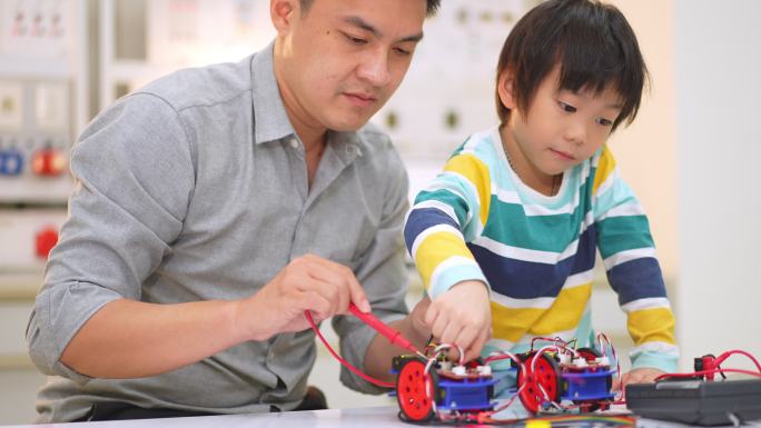 亚洲学生和教师在科学课上使用电子仪表和笔记本电脑构建自动驾驶机器人汽车的原型