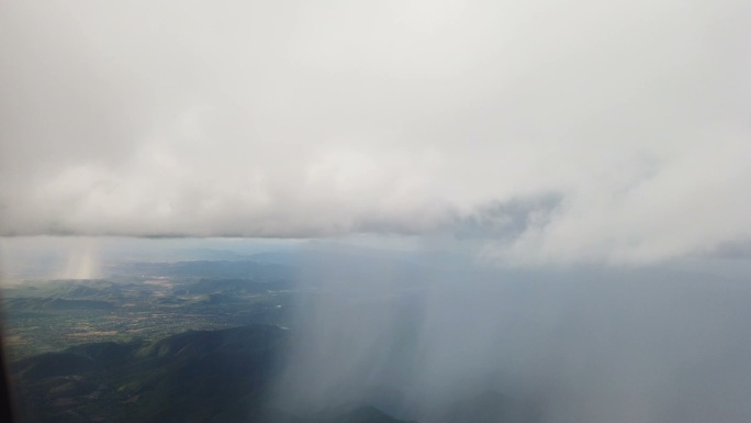 从飞机的窗户望去，天空乌云密布，雨点落下