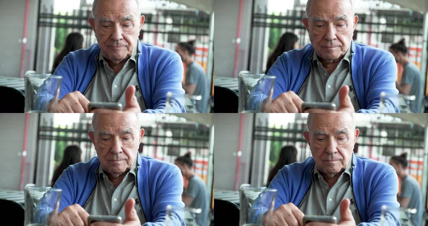 一位严肃的老年人在啤酒厂露台喝啤酒时看着他的智能手机