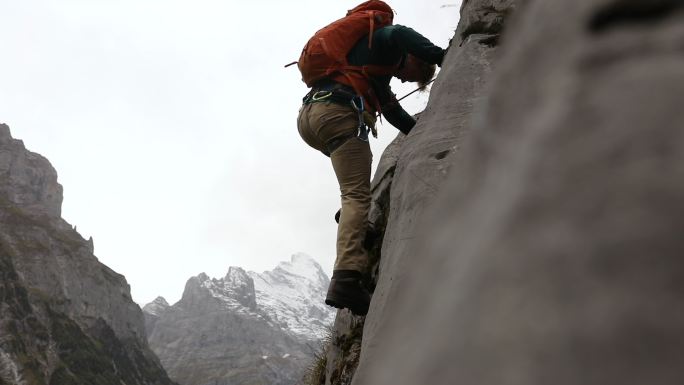 男登山运动员登上陡峭的岩石表面