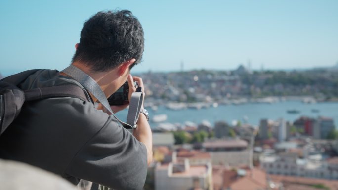 年轻的男性摄影师和摄像师旅游期间在历史建筑顶部拍摄城市照片和视频