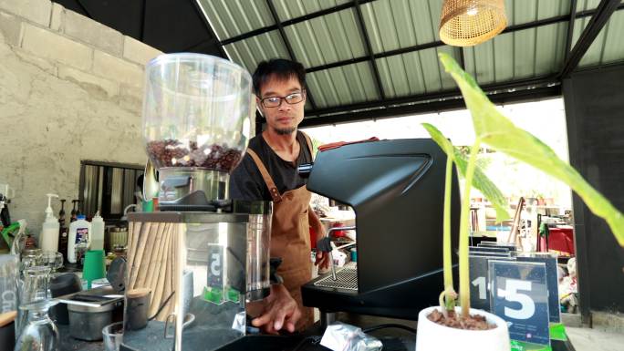 一位亚洲咖啡师在咖啡店为顾客煮咖啡