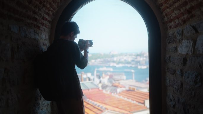 年轻的男性摄影师和摄像师旅游期间，从历史建筑的窗口拍摄城市的照片和视频