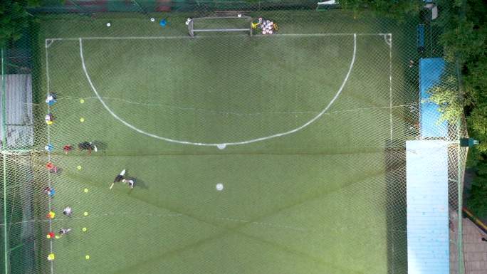 俯拍楼顶足球场，儿童在训练