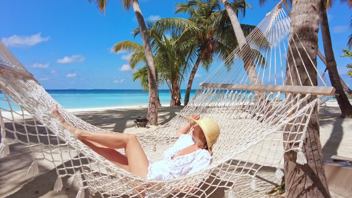 在热带岛屿度假胜地吊床上休息的女人