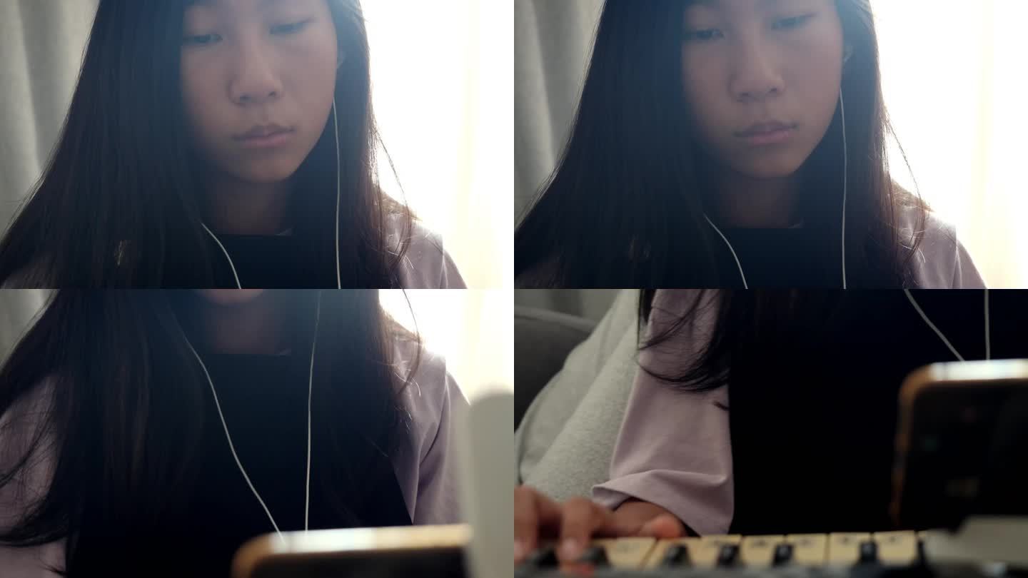 亚洲女孩在家里玩手机游戏的哥哥旁边的沙发上通过手机应用程序学习键盘乐器，生活方式理念。