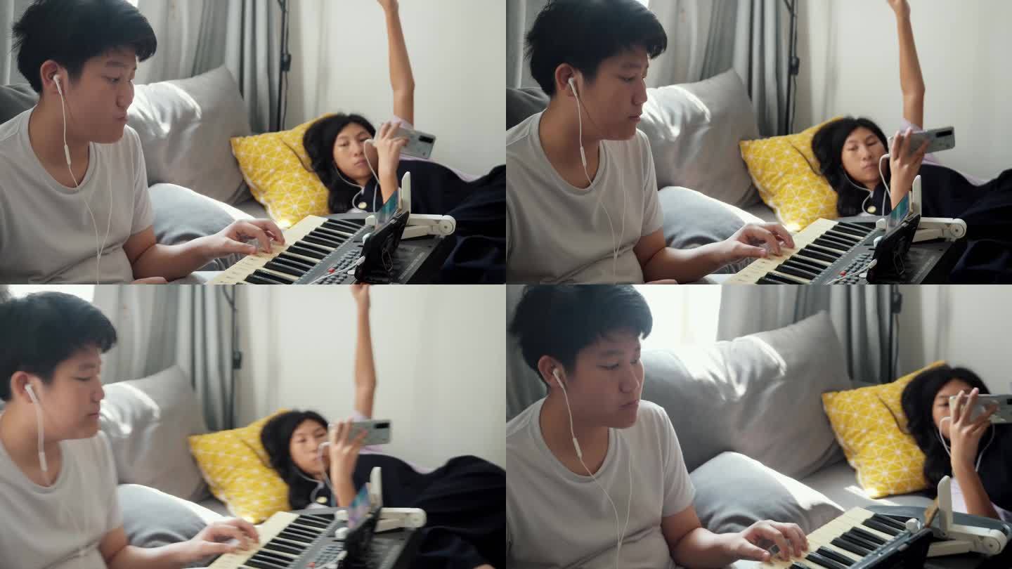亚洲男孩在家里靠窗的沙发上通过手机应用程序学习键盘乐器，生活方式理念。