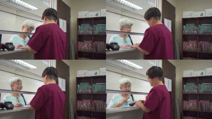 亚洲华人老年女性用信用卡支付医疗账单点击诊所女护士持有的信用卡读取器NFT