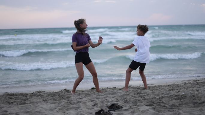 青少年女孩和男孩在海滩上练习空手道