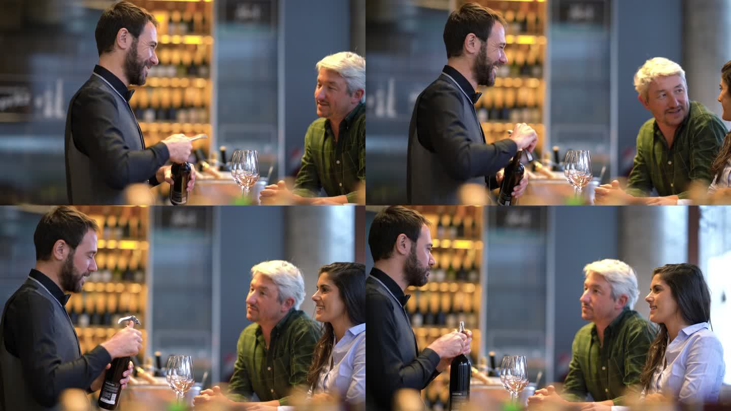 在品酒会上，一对幸福的夫妇在专业品酒师微笑着打开葡萄酒时与他交谈
