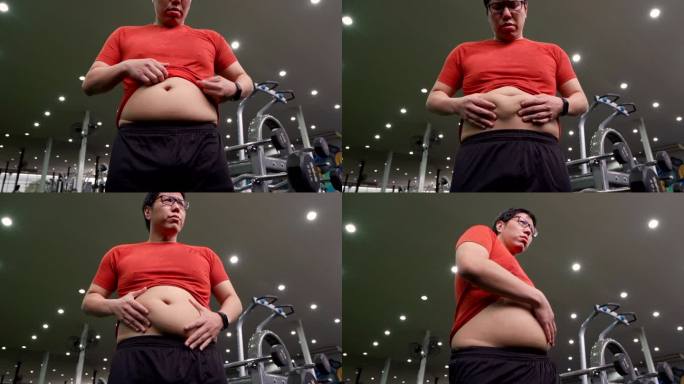 SLO MO大个子亚洲男人看着镜子里的肚子大个子。
