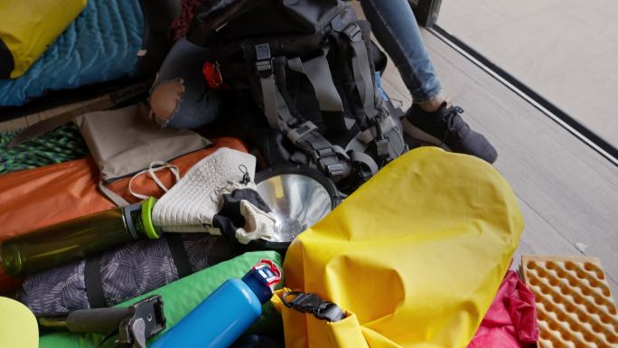 西班牙裔年轻女子打包露营和徒步旅行装备准备打包旅行的慢镜头全景