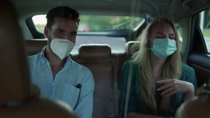 一男一女戴着防护面罩，坐在众包出租车的后座上，一边聊天一边享受骑行