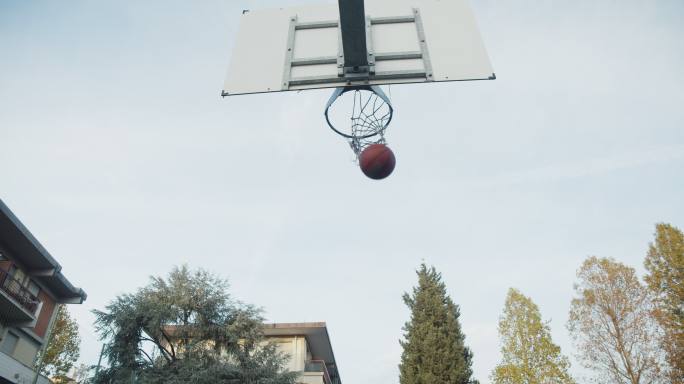一个年轻的成年男子在篮球场上进球的低角度视图