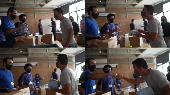 志愿者在慈善捐赠中心为一名男子捐赠衣服-戴防护面罩