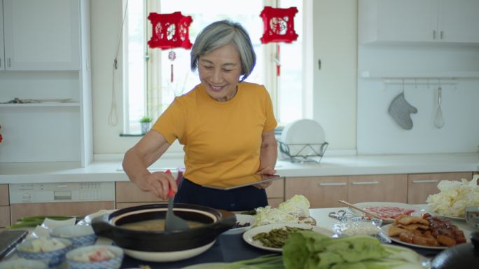 亚洲资深女性手持数字平板电脑搅拌火锅