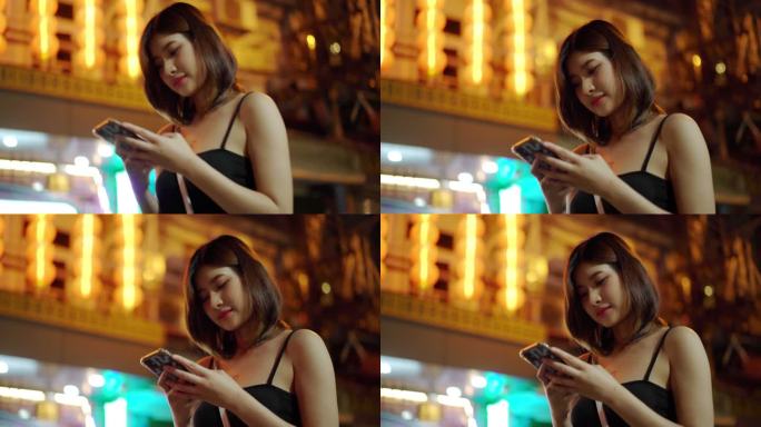 泰国曼谷耀瓦拉特区的一个夜市上，年轻女子在附近使用智能手机