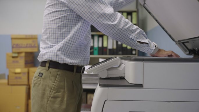 在复印室使用复印机复印文件的男性上班族。