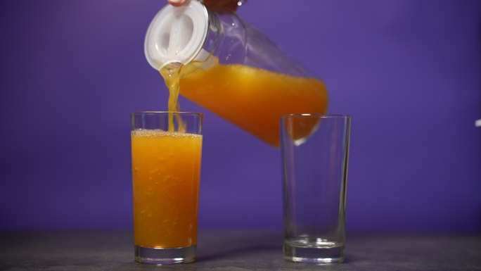 将橙汁倒入玻璃杯下落流淌倒入杯中