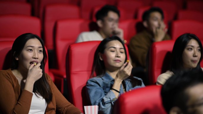 在电影放映期间，一对亚裔中国夫妇晚进电影院，试图穿过其他观众到达座位