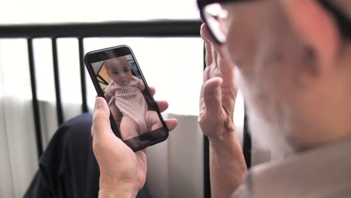 爷爷奶奶在家里用智能手机与孙子孙女视频通话