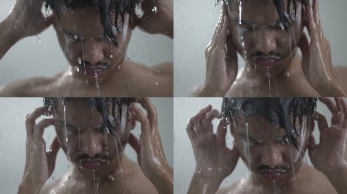 一个年轻人在浴室淋浴下洗黑发的特写镜头