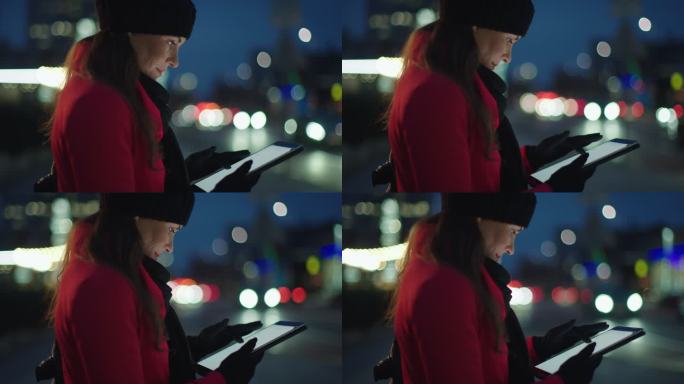 身穿红色外套的女士在城市人行道上使用平板电脑