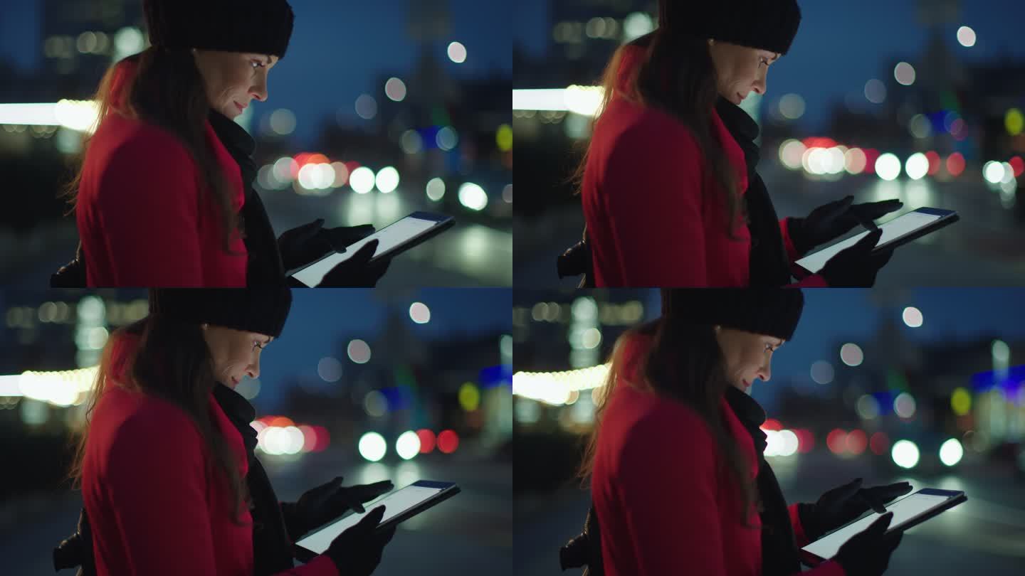 身穿红色外套的女士在城市人行道上使用平板电脑