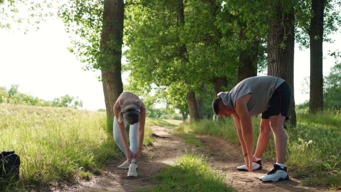 年轻的成年夫妇在大自然中锻炼，拉伸运动